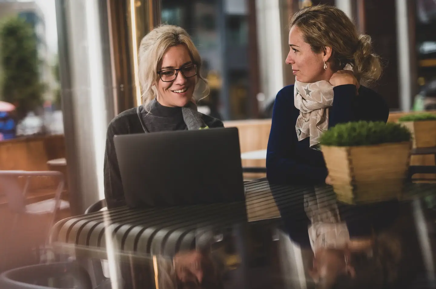 To personer i hyggelig samtale med hver sin laptop.